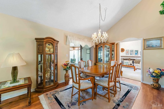 dining room with vaulted ceiling, an inviting chandelier, and wood-type flooring