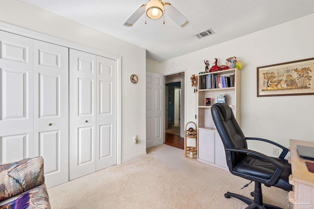 carpeted office featuring ceiling fan and a textured ceiling