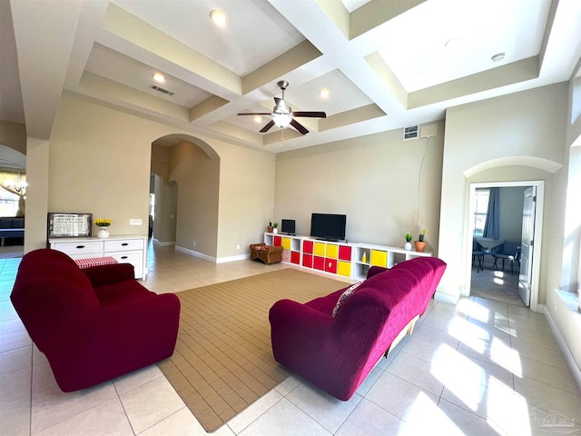 living area featuring coffered ceiling, arched walkways, a ceiling fan, light tile patterned floors, and beamed ceiling