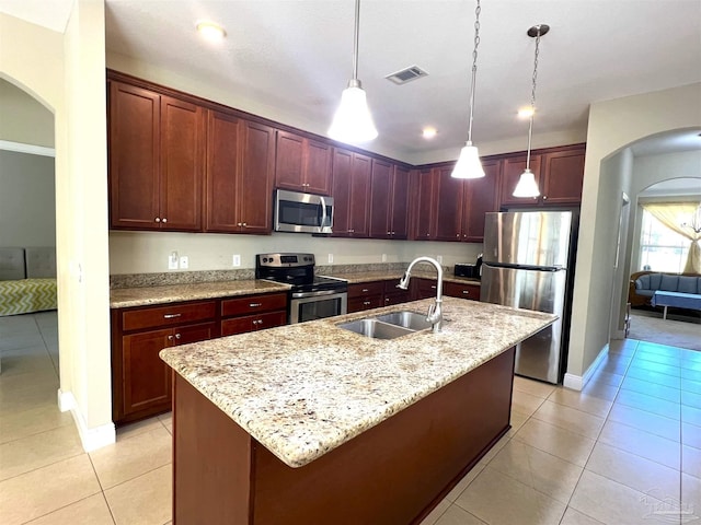 kitchen with stainless steel appliances, a sink, arched walkways, light tile patterned flooring, and decorative light fixtures