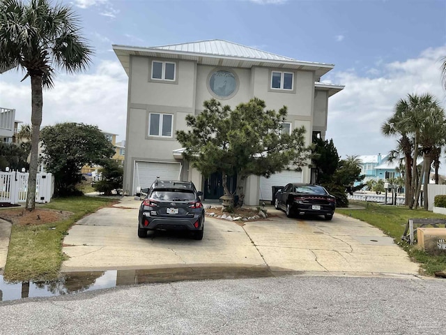 view of front of house with stucco siding, driveway, metal roof, and an attached garage