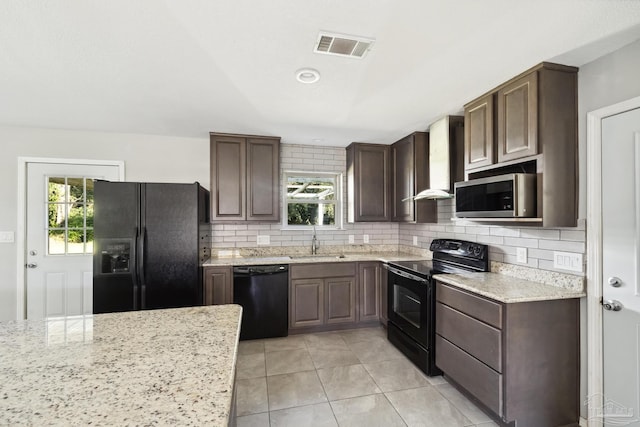 kitchen with dark brown cabinetry, light stone countertops, sink, and black appliances