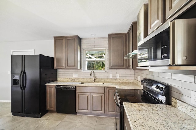 kitchen featuring light stone countertops, tasteful backsplash, sink, black appliances, and light tile patterned flooring