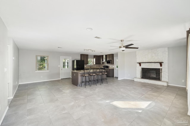 unfurnished living room with a fireplace, light tile patterned floors, and ceiling fan