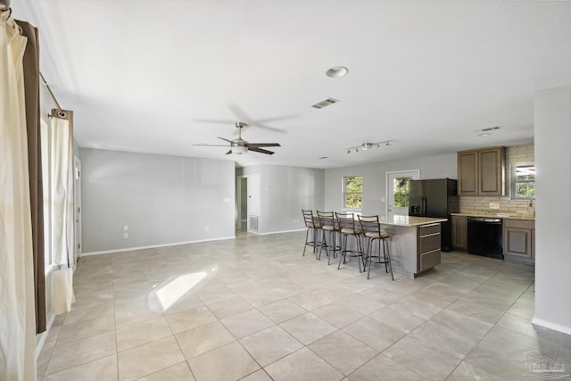 kitchen featuring a kitchen breakfast bar, a center island, a wealth of natural light, and black appliances