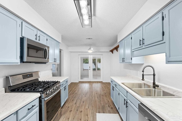 kitchen with sink, french doors, light hardwood / wood-style floors, a textured ceiling, and appliances with stainless steel finishes