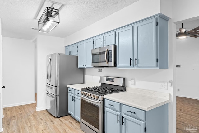 kitchen with ceiling fan, stainless steel appliances, a textured ceiling, and light hardwood / wood-style floors