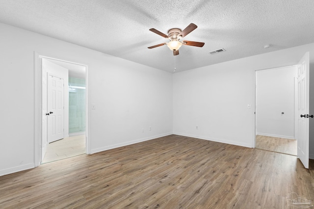 unfurnished room with ceiling fan, a textured ceiling, and light wood-type flooring