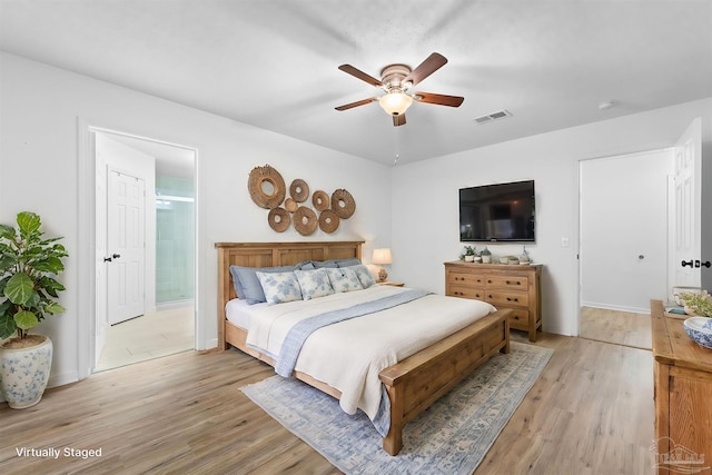 bedroom with ceiling fan, ensuite bathroom, and light wood-type flooring