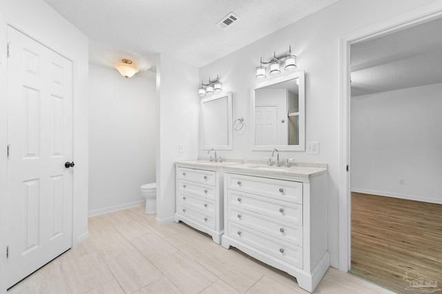 bathroom featuring hardwood / wood-style floors, vanity, a textured ceiling, and toilet