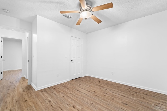 empty room featuring ceiling fan, light hardwood / wood-style floors, and a textured ceiling