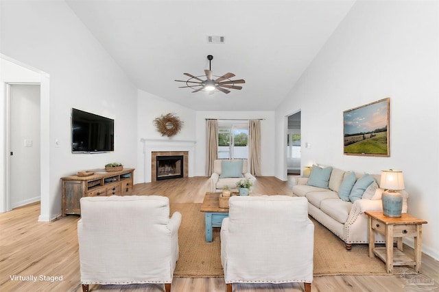 living room with ceiling fan, a fireplace, high vaulted ceiling, and light hardwood / wood-style flooring