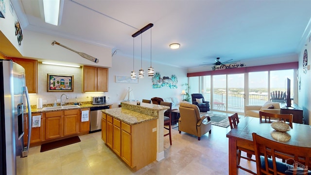 kitchen with light stone counters, ceiling fan, hanging light fixtures, sink, and stainless steel appliances