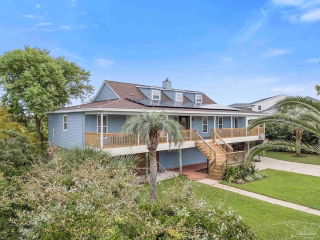 412 Deer Point Dr, Gulf Breeze, FL 32561 - view of front facade featuring a front yard, solar panels, covered porch, a chimney, and stairway