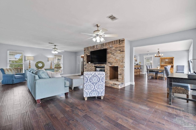 living room with ceiling fan with notable chandelier, a fireplace, and dark hardwood / wood-style floors