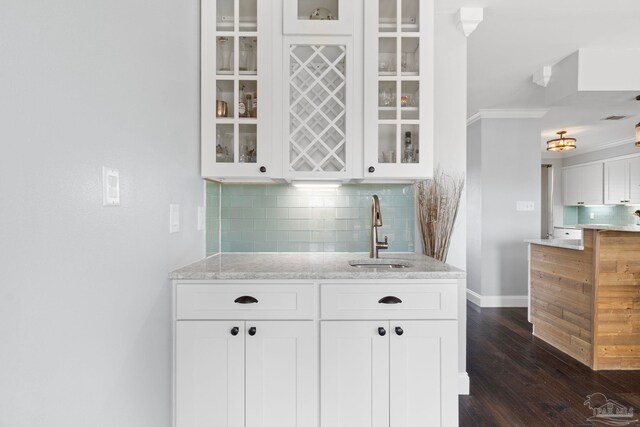 bar featuring white cabinets, sink, tasteful backsplash, dark wood-type flooring, and crown molding