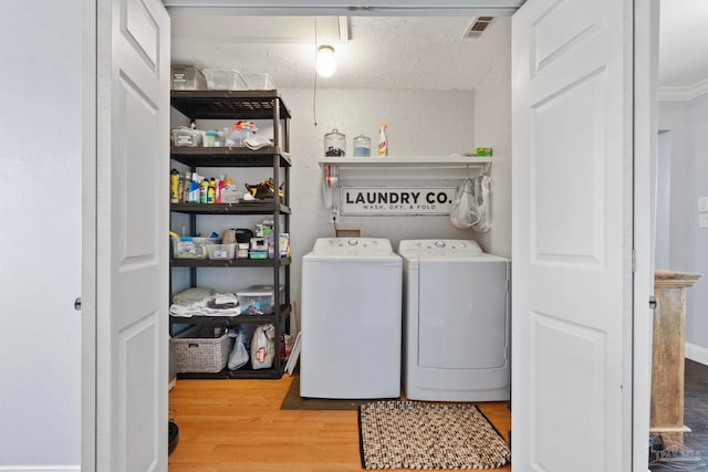 laundry area featuring crown molding, light hardwood / wood-style floors, and washing machine and clothes dryer