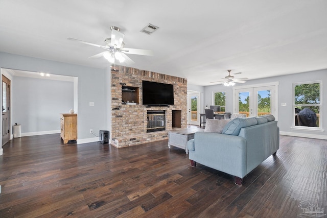 living room with a brick fireplace, dark hardwood / wood-style floors, french doors, and ceiling fan