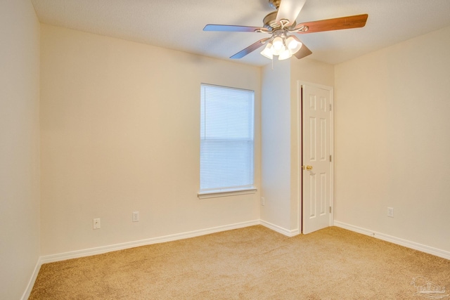 empty room featuring baseboards, a ceiling fan, and light colored carpet