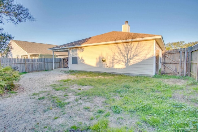 rear view of house featuring a fenced backyard and a chimney