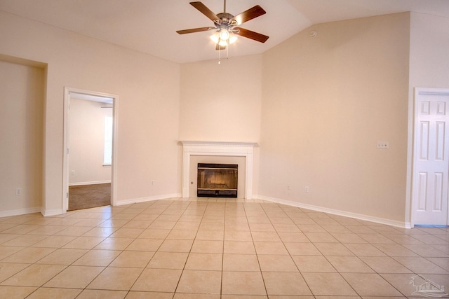 unfurnished living room featuring baseboards, a ceiling fan, a glass covered fireplace, lofted ceiling, and light tile patterned flooring