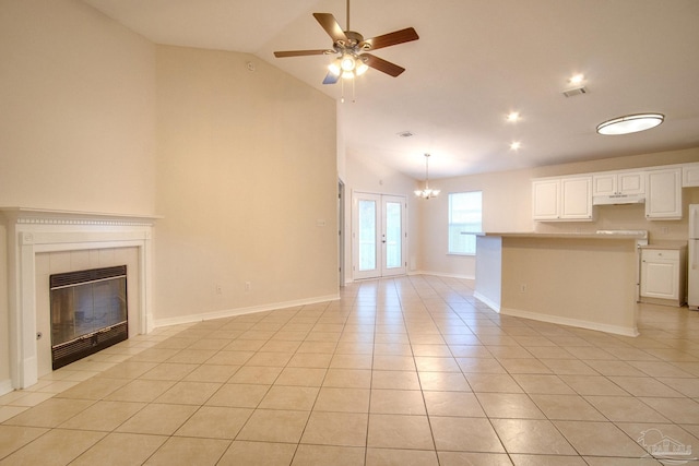 unfurnished living room with light tile patterned floors, ceiling fan with notable chandelier, a fireplace, visible vents, and vaulted ceiling