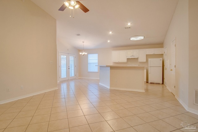 kitchen featuring a center island, light tile patterned floors, light countertops, freestanding refrigerator, and white cabinetry