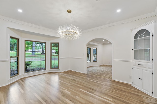 unfurnished dining area with ornamental molding, a chandelier, and light wood-type flooring