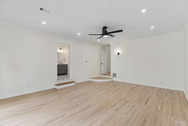 unfurnished living room with sink, crown molding, ceiling fan, and light wood-type flooring