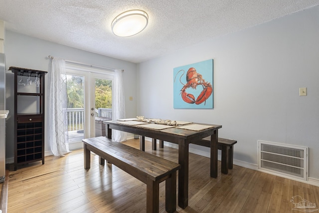 dining space with french doors, hardwood / wood-style floors, and a textured ceiling