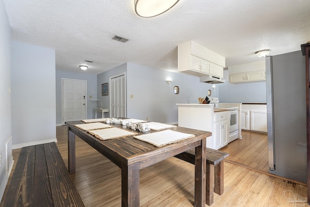 dining area with light hardwood / wood-style flooring and a textured ceiling