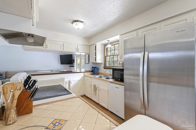 kitchen with sink, white cabinetry, a textured ceiling, stainless steel refrigerator, and white dishwasher