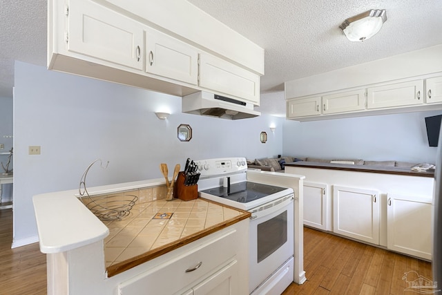 kitchen with light hardwood / wood-style flooring, tile countertops, white cabinets, and white range with electric stovetop