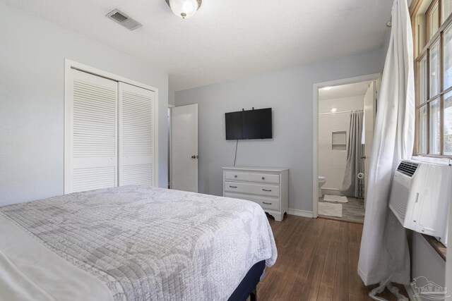 bedroom featuring dark wood-type flooring, ensuite bathroom, and a closet