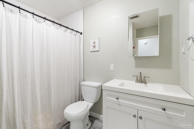 bathroom featuring vanity, toilet, a textured ceiling, and walk in shower