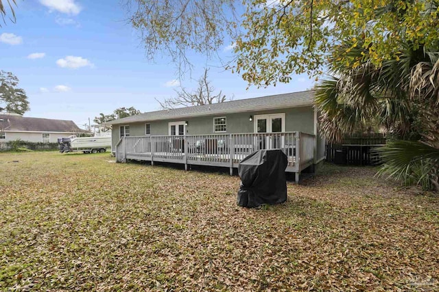 rear view of house with french doors, a deck, and a lawn