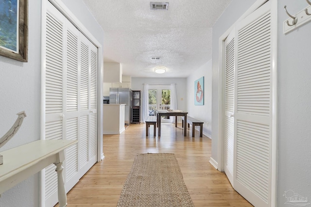 hallway with a textured ceiling and light hardwood / wood-style floors