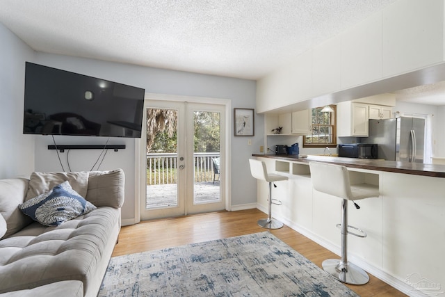 living room featuring french doors, a textured ceiling, and light hardwood / wood-style flooring