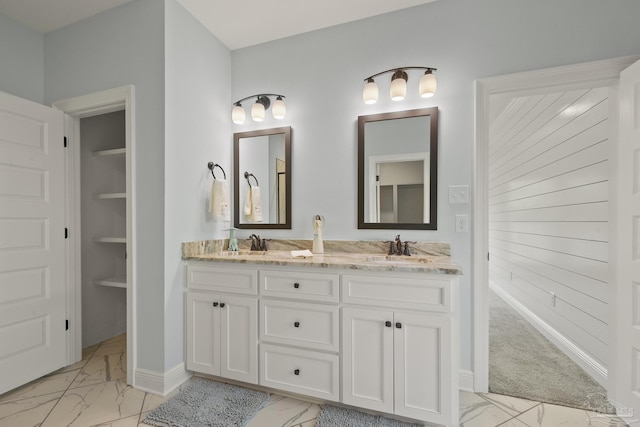 full bathroom featuring a sink, baseboards, double vanity, and marble finish floor