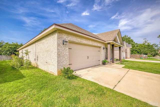 view of side of property featuring an attached garage, a lawn, fence, brick siding, and driveway