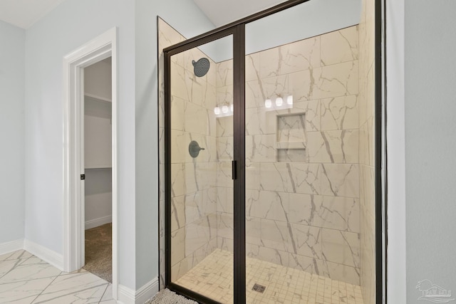 full bath with a stall shower, marble finish floor, baseboards, and a spacious closet