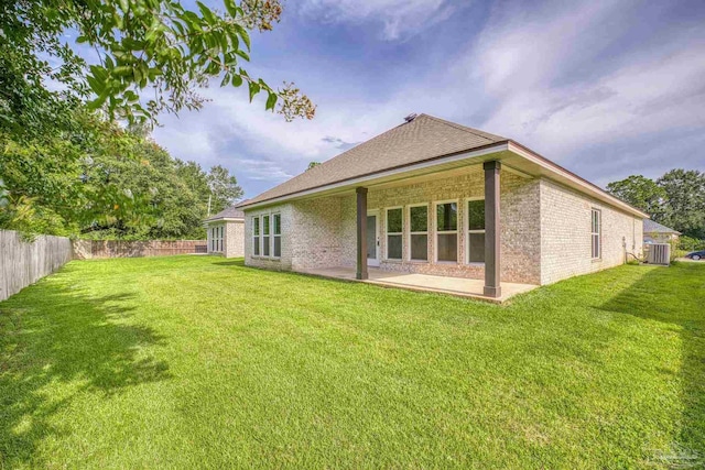 rear view of house featuring a patio, brick siding, a fenced backyard, central AC, and a lawn