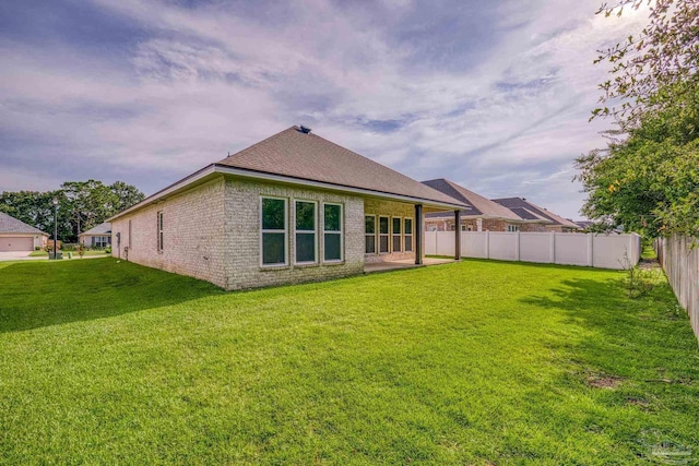 back of property featuring brick siding, a lawn, a patio, and fence private yard