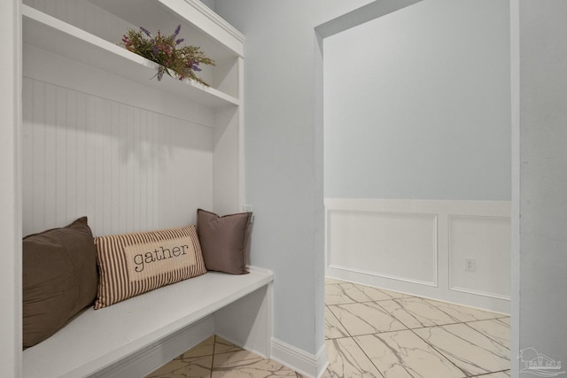 mudroom with a decorative wall, wainscoting, and marble finish floor