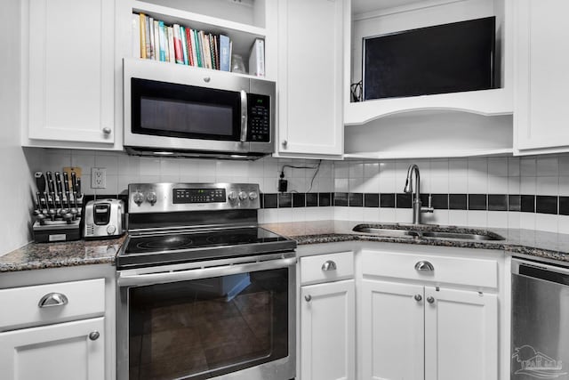 kitchen featuring white cabinetry, appliances with stainless steel finishes, sink, and dark stone counters