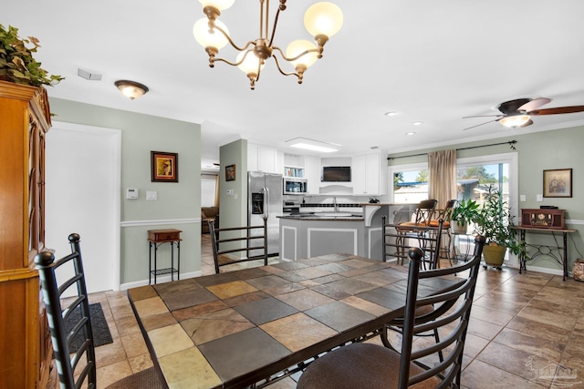 dining space featuring ornamental molding, sink, and ceiling fan with notable chandelier