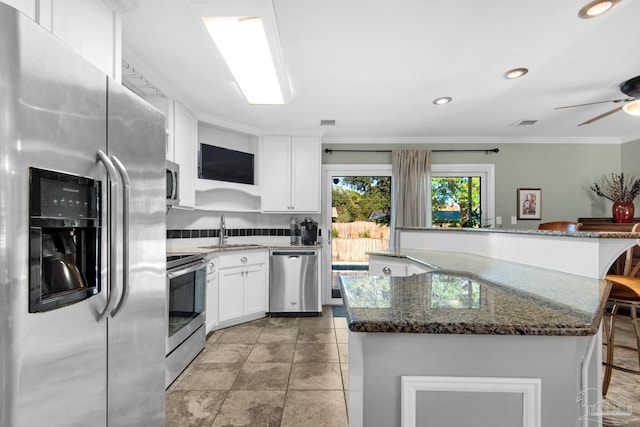 kitchen featuring white cabinetry, sink, a breakfast bar area, backsplash, and stainless steel appliances