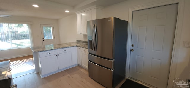 kitchen with kitchen peninsula, white cabinets, stainless steel refrigerator with ice dispenser, and light wood-type flooring