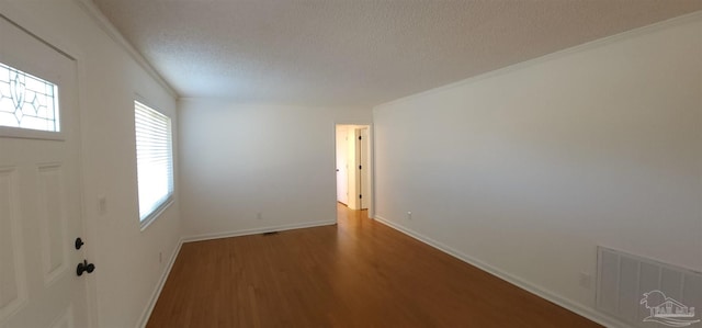 foyer with hardwood / wood-style flooring, ornamental molding, a textured ceiling, and a wealth of natural light