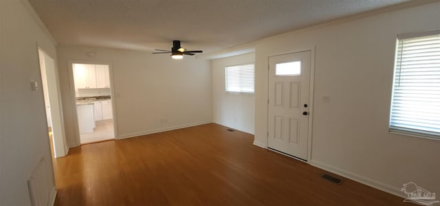 foyer with ceiling fan, crown molding, light hardwood / wood-style floors, and a textured ceiling